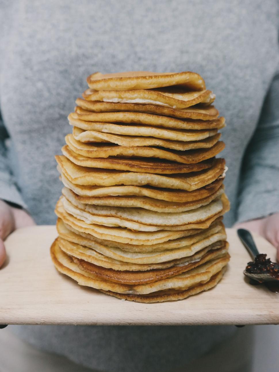 Free Image of Tall stack of pancakes held on wooden board by person 