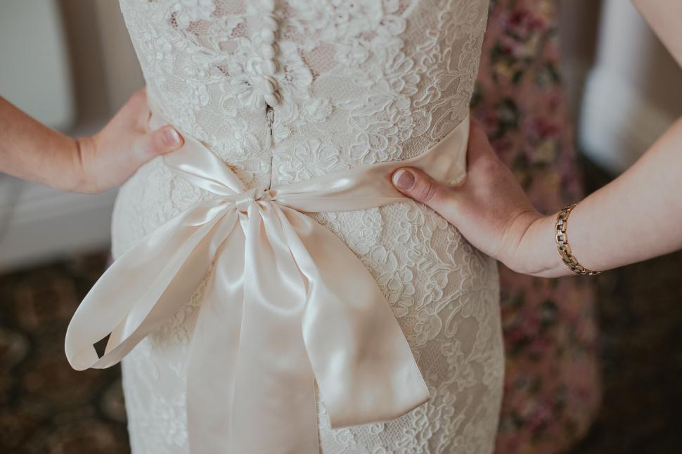 Free Image of Bride adjusting her lace wedding dress bow tie. 