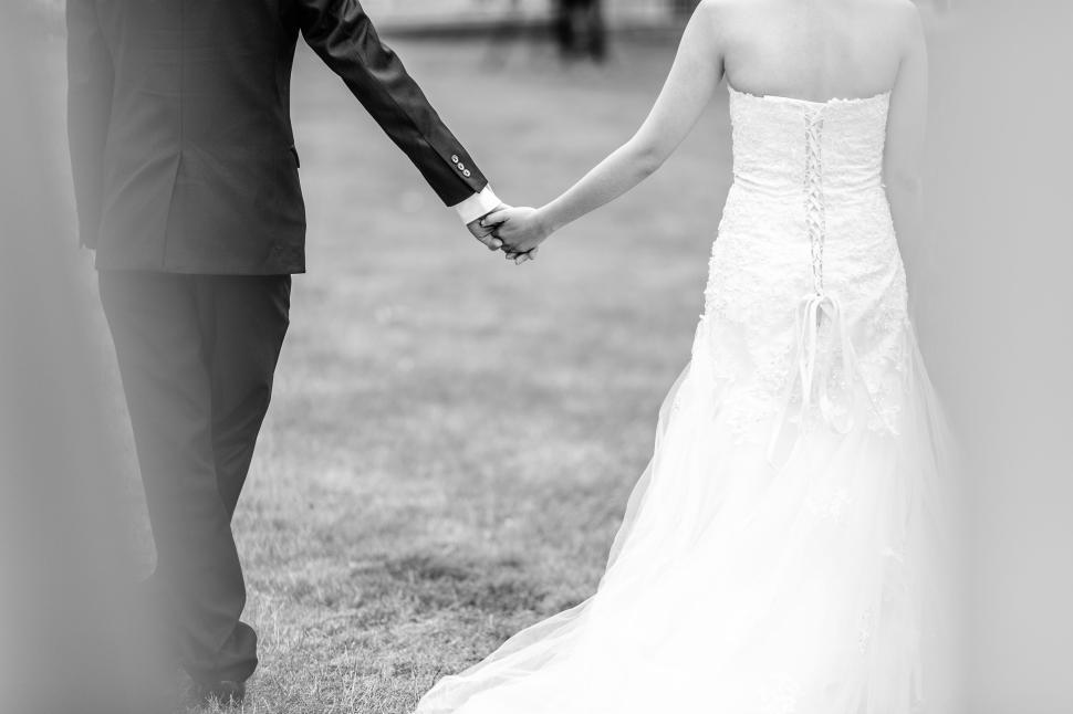Free Image of Bride and groom holding hands in wedding attire 
