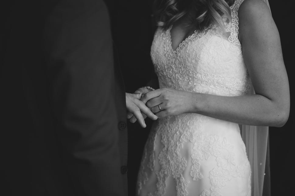 Free Image of Bride placing ring on groom s finger in black and white 