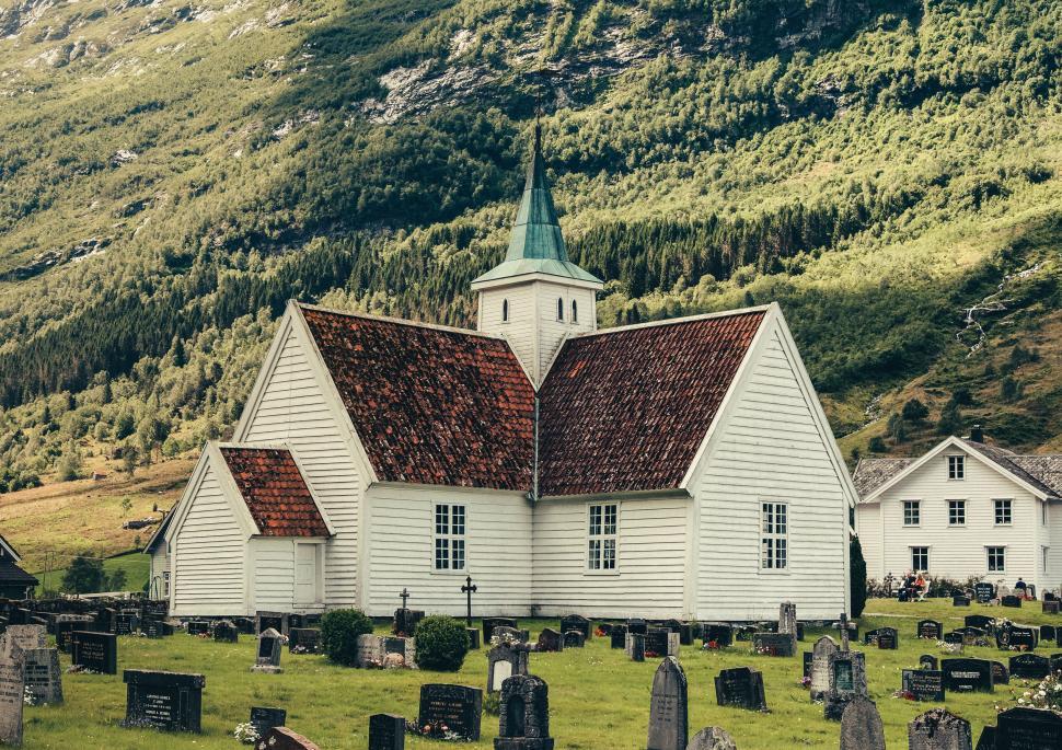 Free Image of White church with cemetery nestled in green valley 