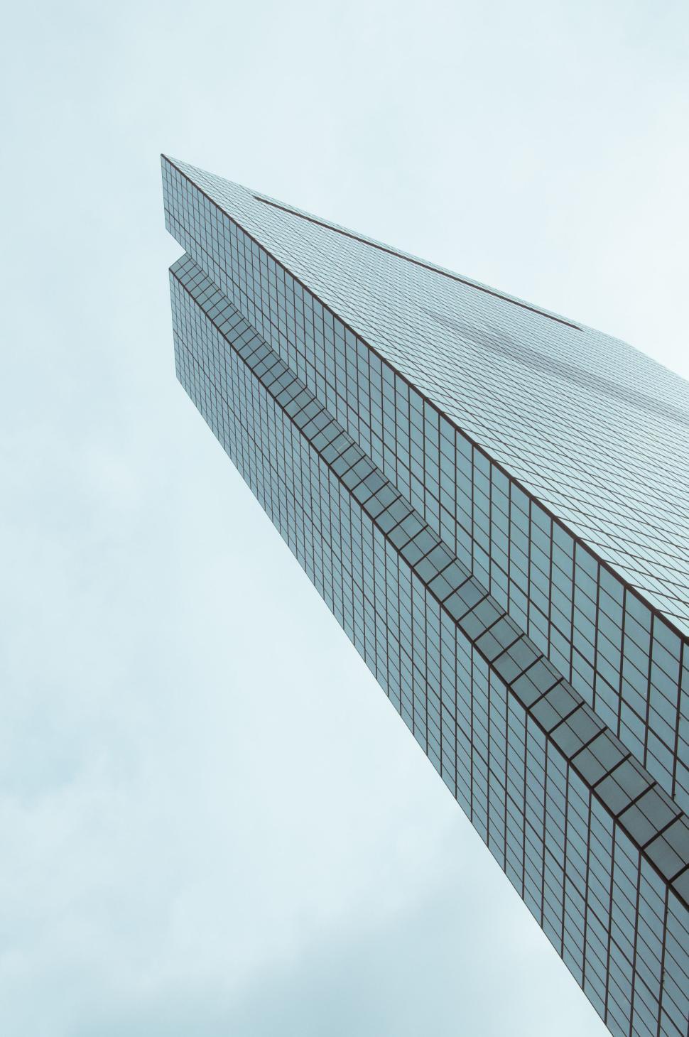 Free Image of Modern skyscraper reaching up into cloudy blue sky 
