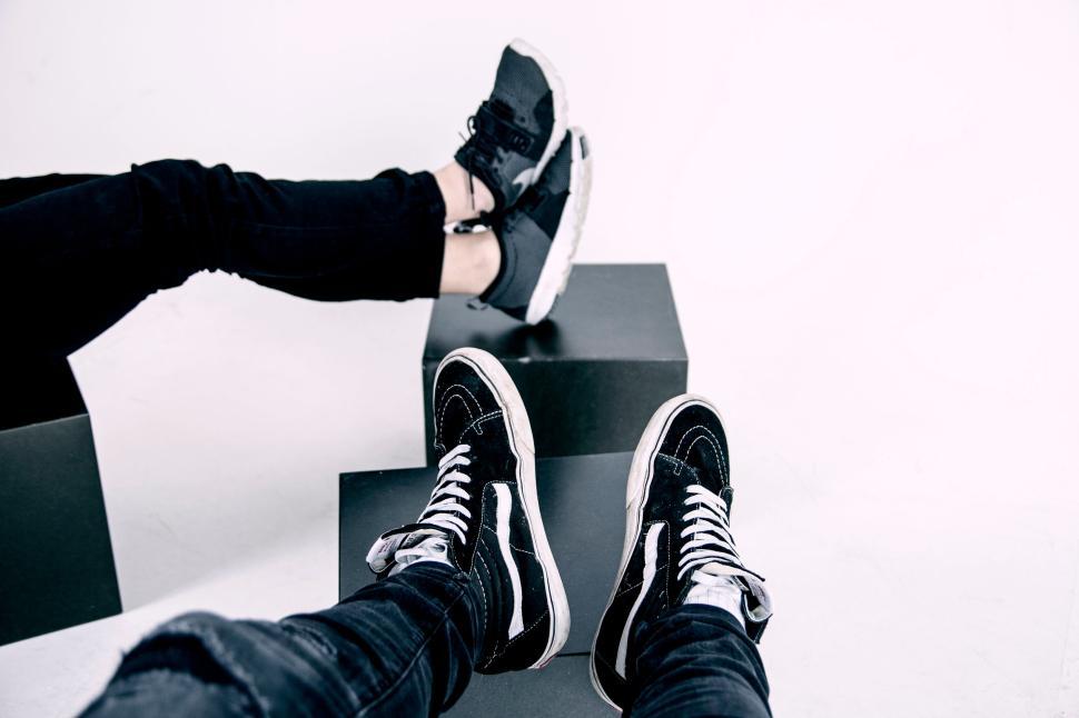 Free Image of Two people sitting with stylish black and white shoes 