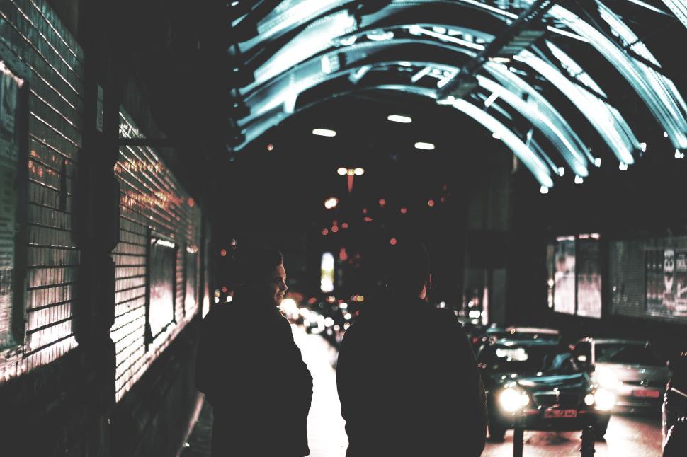 Free Image of Two people walking under illuminated arc in the night 