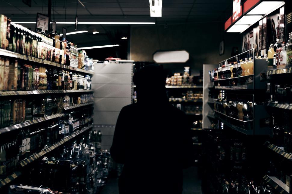 Free Image of Person in dark jacket walking through grocery store aisle 