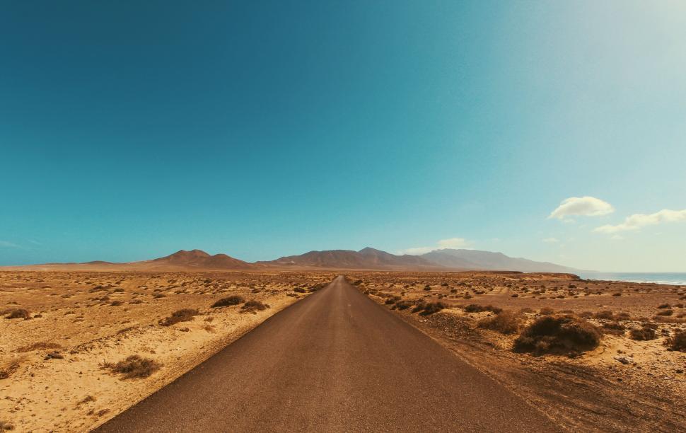Free Image of Long straight road stretching into desert with mountains 
