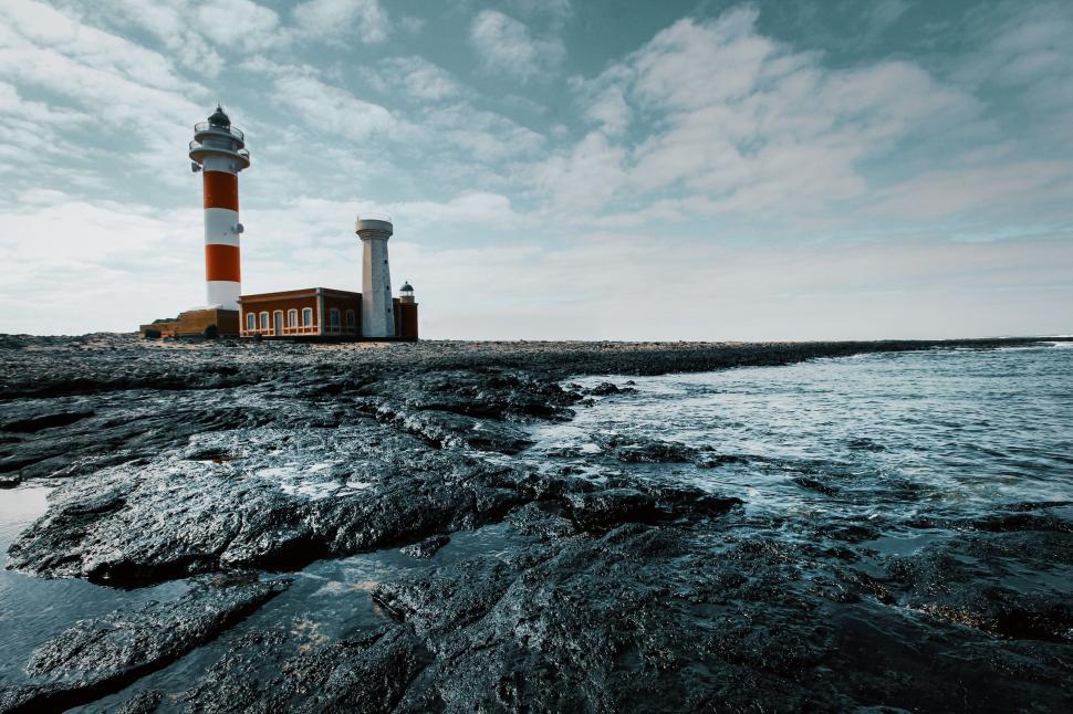Free Image of Dramatic lighthouse on rocky shore under cloudy sky 