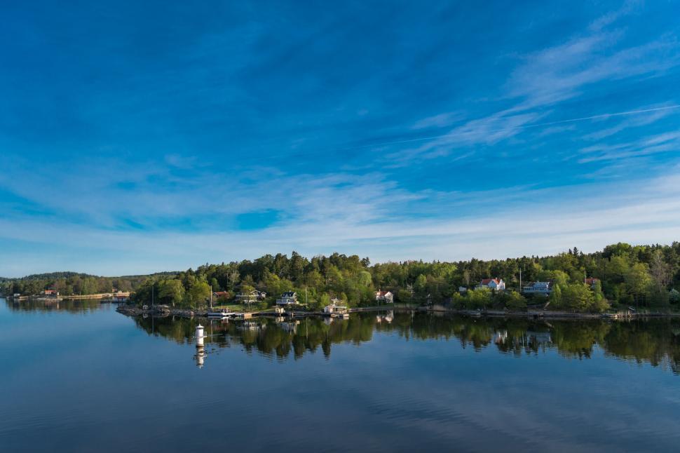 Free Image of Serene lake with green trees under a clear blue sky. 