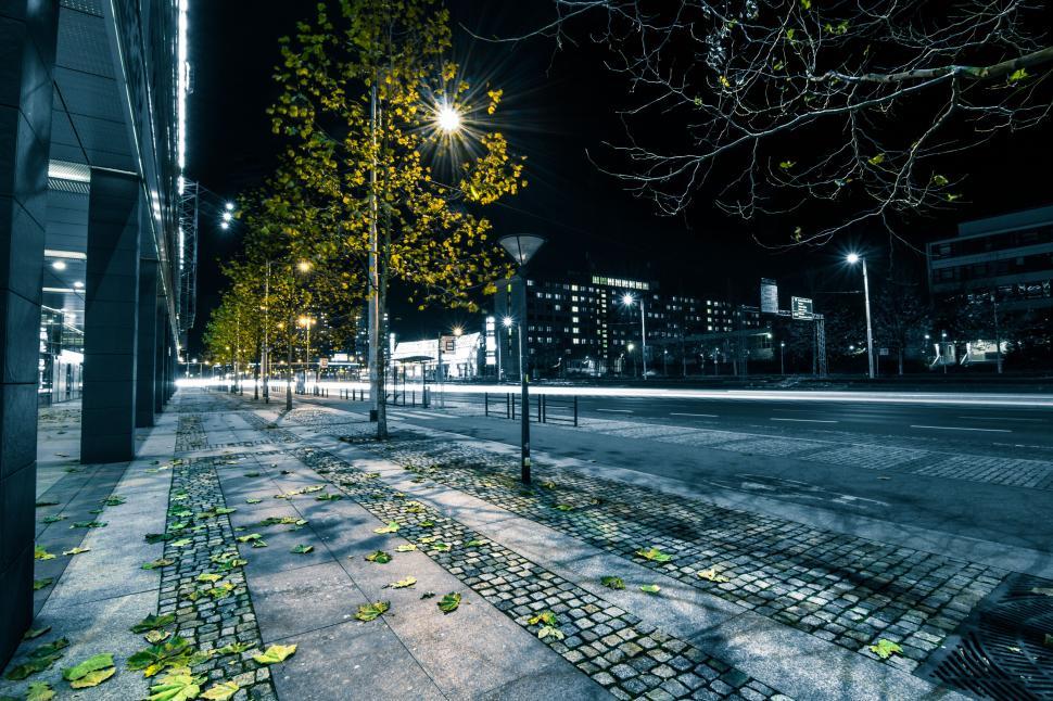 Free Image of Empty nighttime city street with bright streetlamps. 