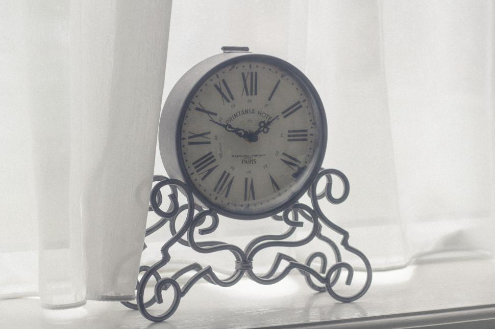 Free Image of Vintage clock on decorative stand with flowing curtains. 