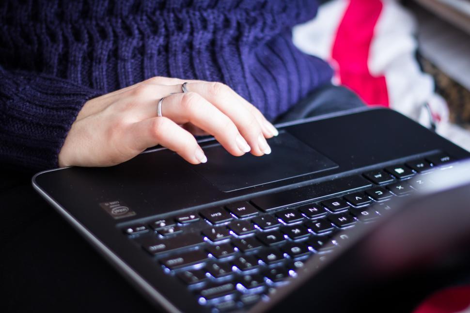 Free Image of Woman s hand using a laptop trackpad with a ring on. 