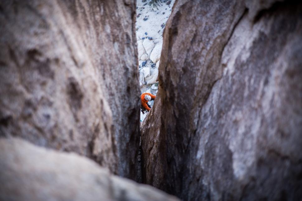 Free Image of Climber navigating narrow crevice between rock walls. 