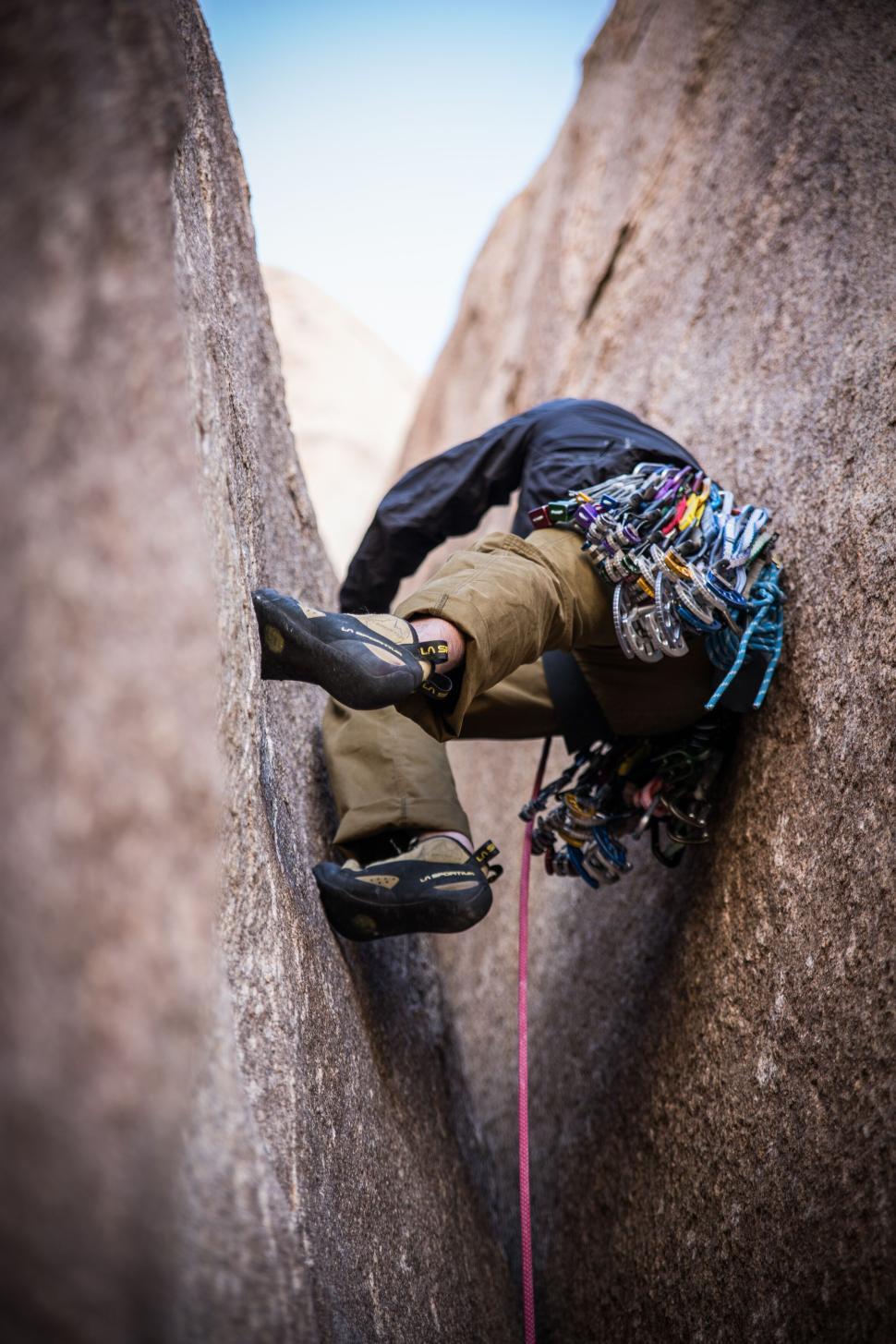 Free Image of Climber squeezing through tight rock formations climb. 