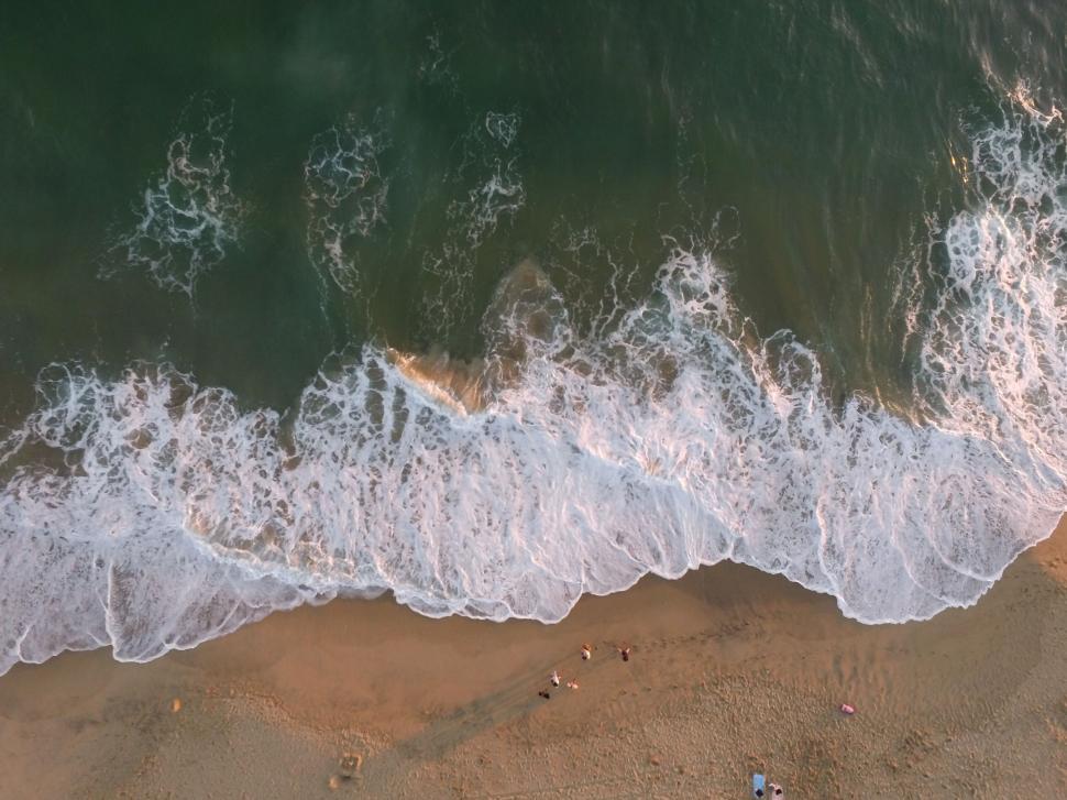 Free Image of Aerial view of ocean waves crashing on sandy shore. 