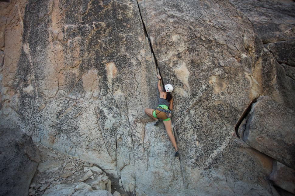 Free Image of Woman rock climbing a large natural stone formation. 