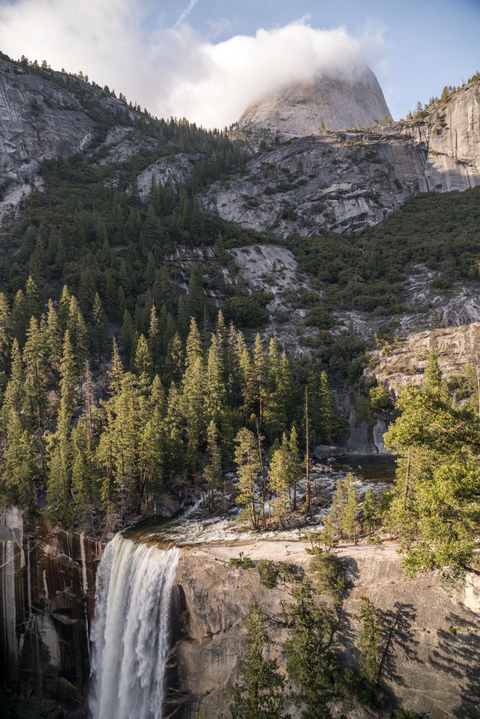 Free Image of Waterfall cascading amidst lush greenery and mountains. 