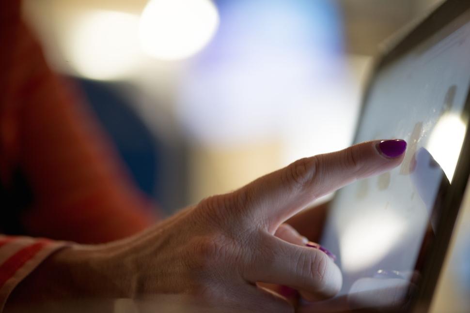 Free Image of Finger touching tablet screen with light background blur. 
