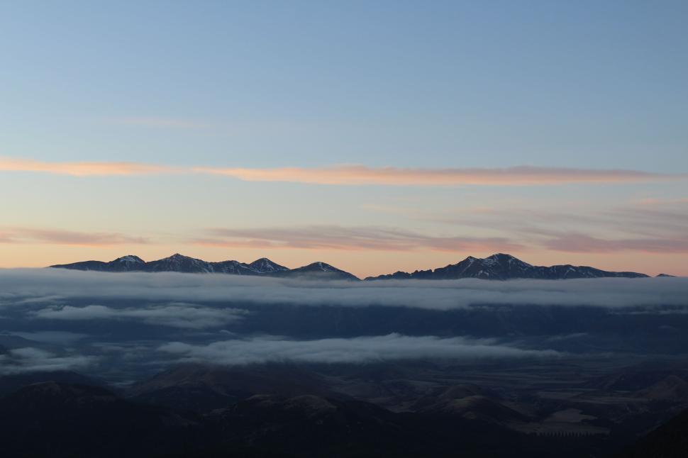 Free Image of Mountain range with clouds resting above the peaks. 