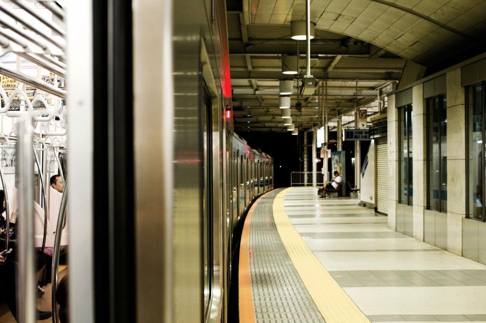 Free Image of Curved train platform with passengers seated inside train 