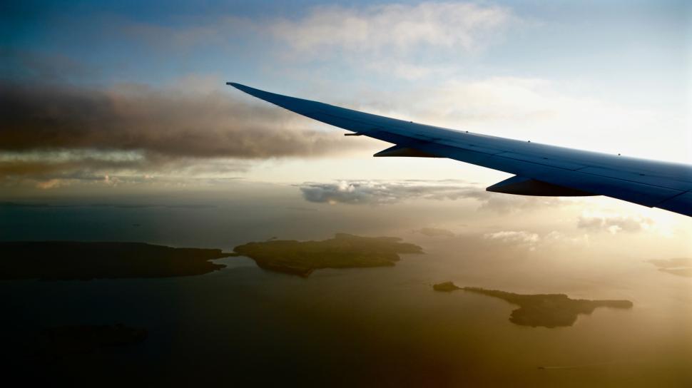 Free Image of Airplane wing over ocean view during scenic sunset flight 