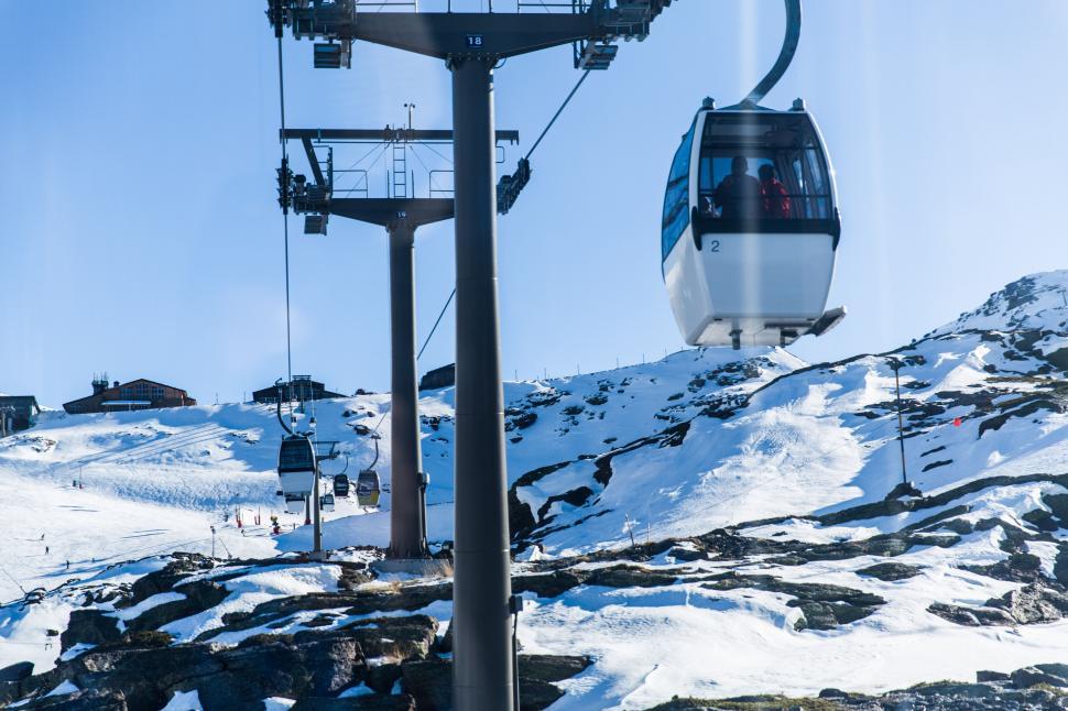 Free Image of Ski lift transporting passenger up snow-covered mountain 