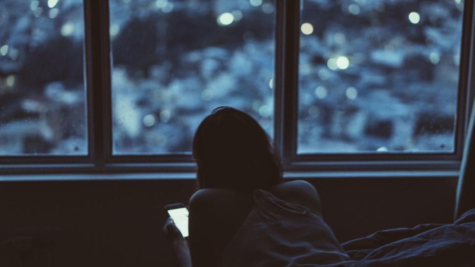 Free Image of Silhouette of a person using a smartphone near window. 