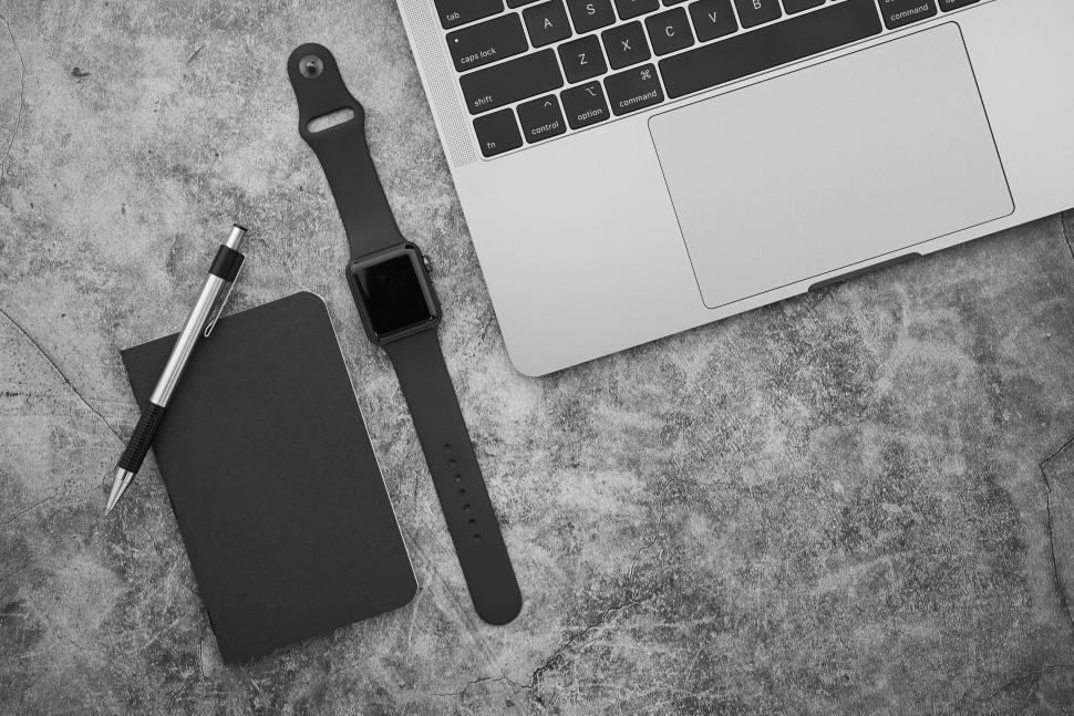 Free Image of Smartwatch, notebook, pen, and laptop on grey surface. 
