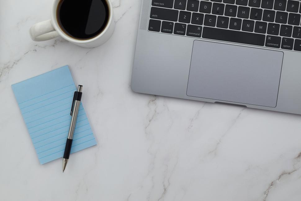 Free Image of Laptop with coffee and blue notepad on marble surface 