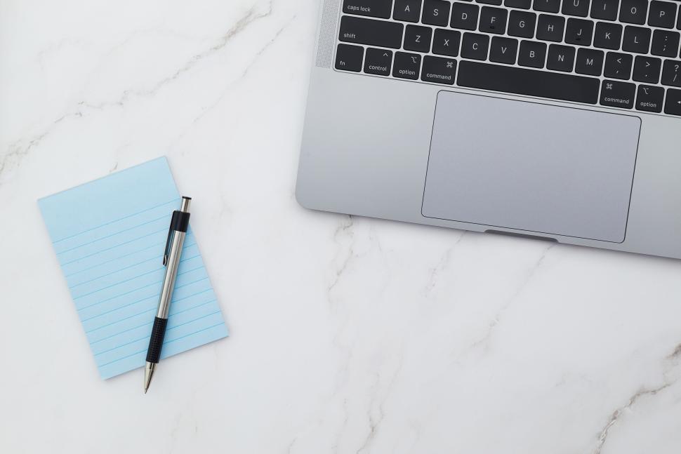 Free Image of Simple desk setup with a laptop, pen, and notepad 