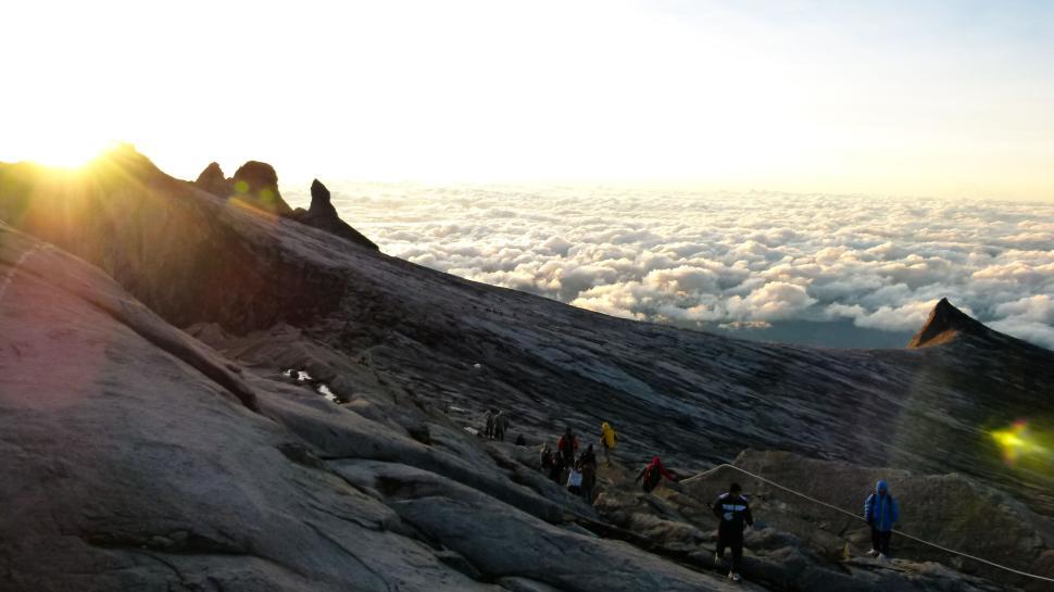 Free Image of Descent from a mountain peak at sunrise amidst clouds 
