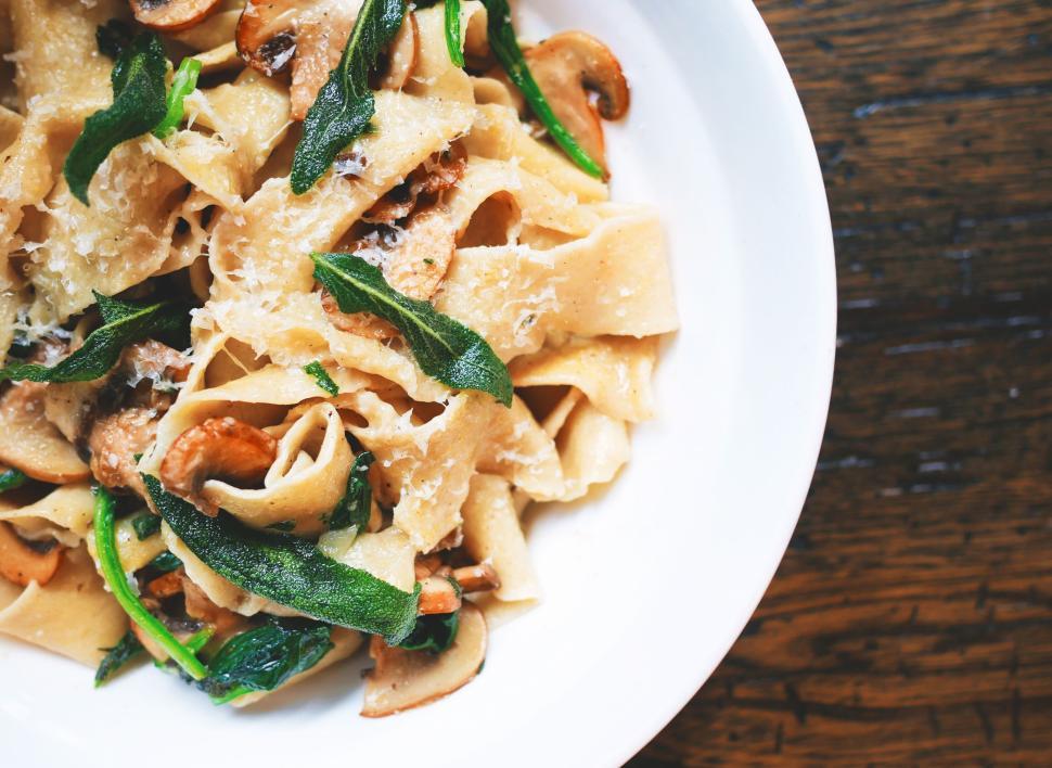 Free Image of Mushroom and spinach pasta garnished with cheese in bowl 