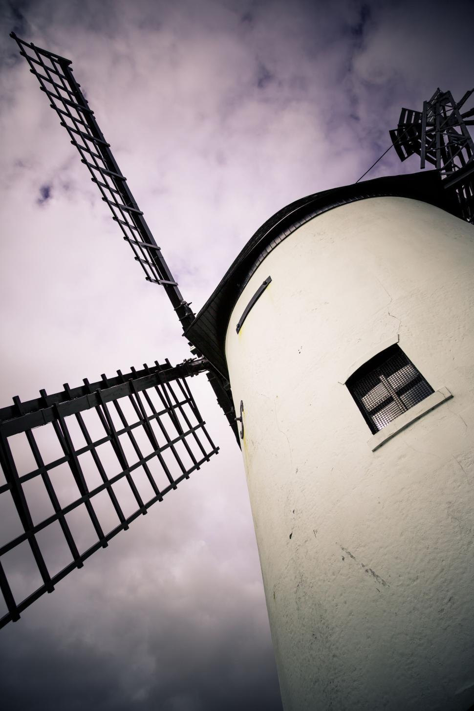 Free Image of Windmill towering against a cloudy sky in perspective. 
