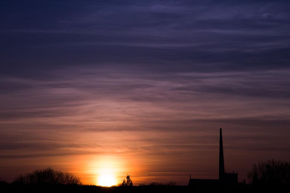 Free Image of Beautiful sunset with silhouetted trees and structures. 