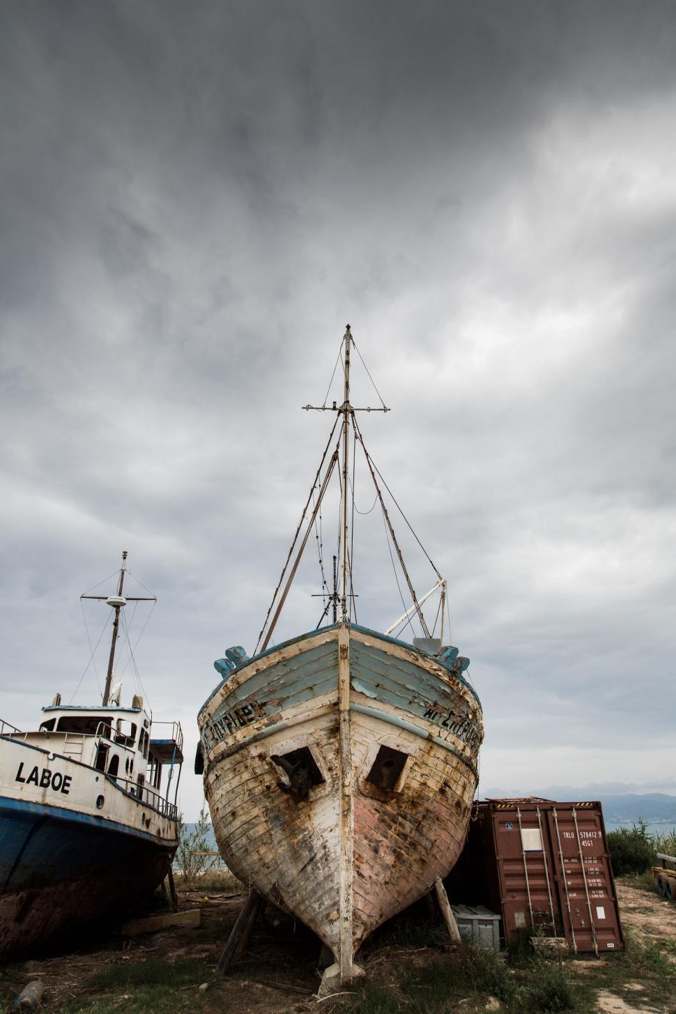 Free Image of Old rustic boats at a shipyard under a cloudy sky 