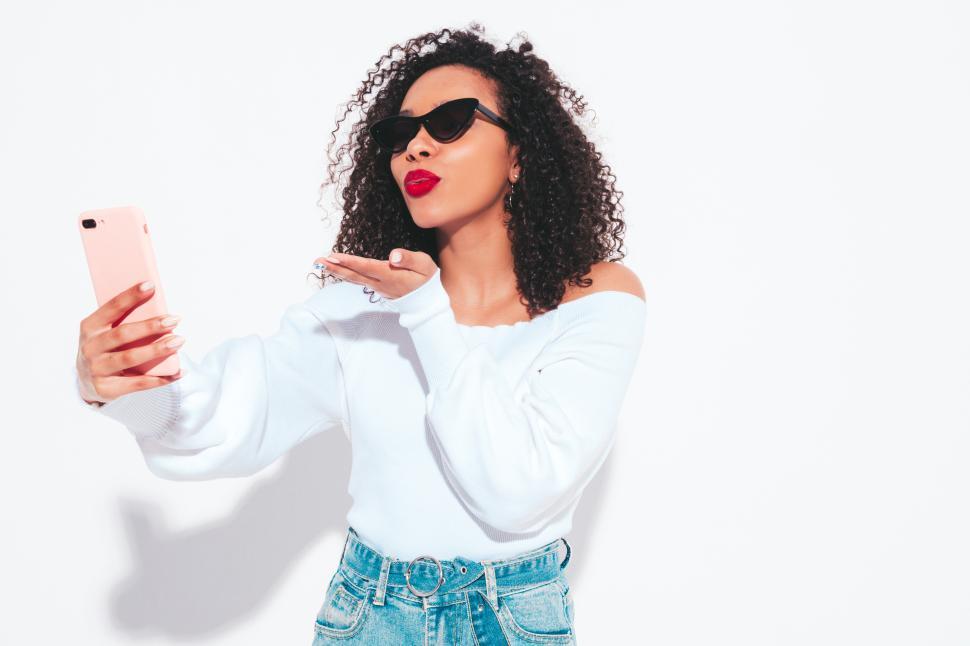 Free Image of Woman taking selfie and blowing kiss on white background. 