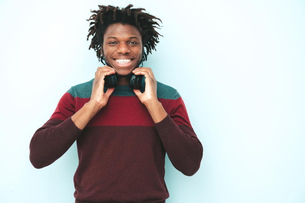 Free Image of Man with dreadlocks and headphones in sweater smiling. 