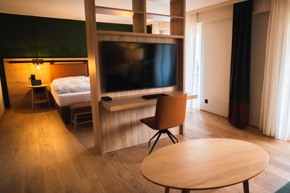 Free Image of Modern hotel room with wooden decor and large TV 