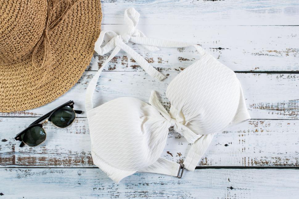 Free Image of Straw hat, white bikini top, and sunglasses on table 