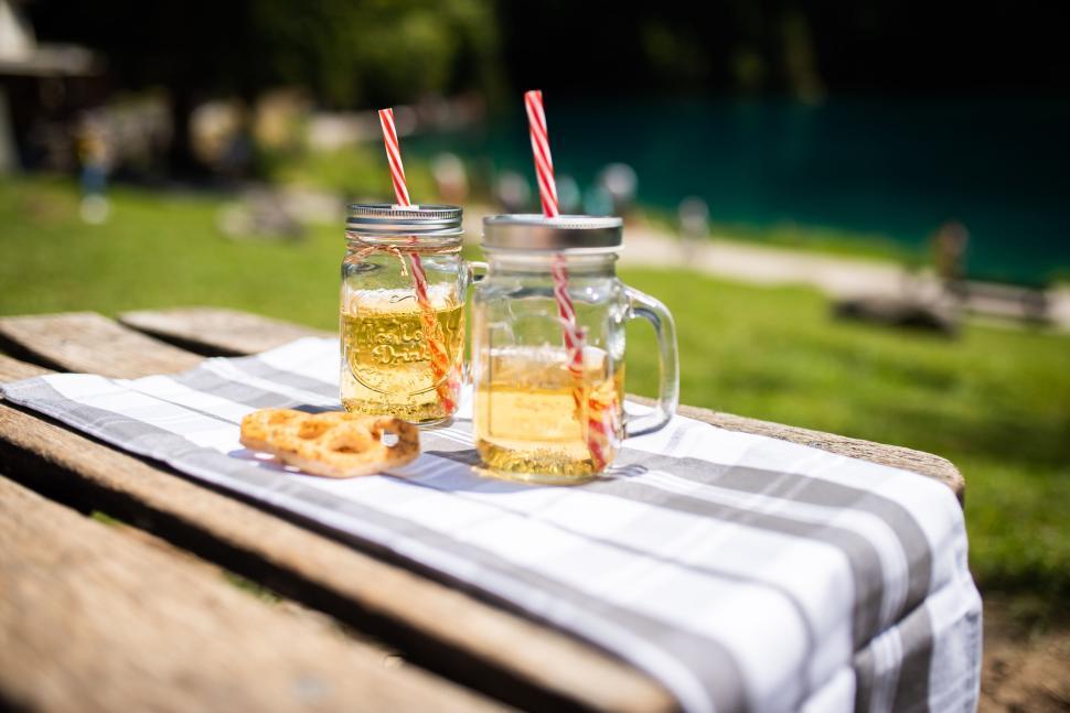 Free Image of Two mason jar drinks and a pastry on a picnic table 