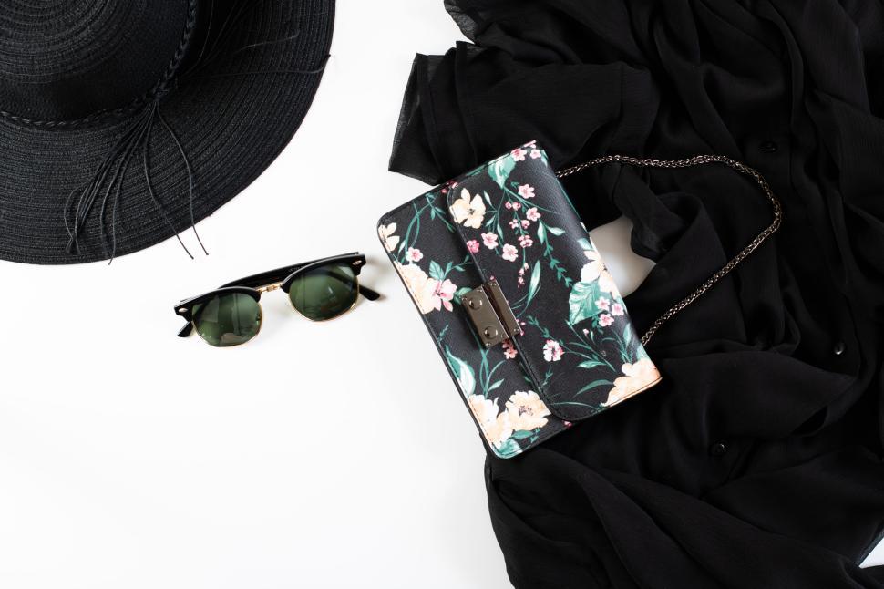 Free Image of Flat lay of hat, sunglasses, and floral purse on fabric 