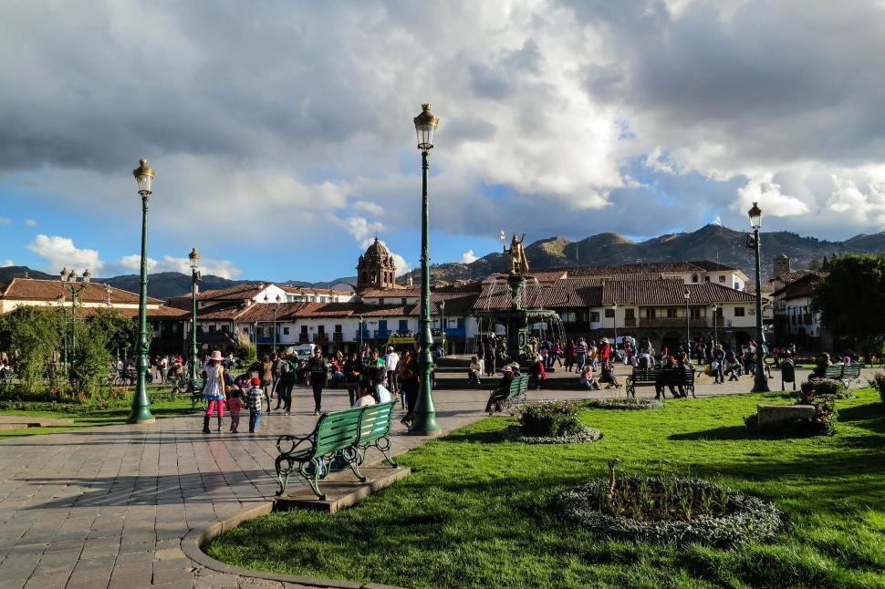 Free Image of Busy town square with people under a cloudy blue sky 