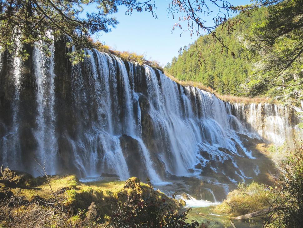 Free Image of Beautiful cascading waterfall flowing between green trees 