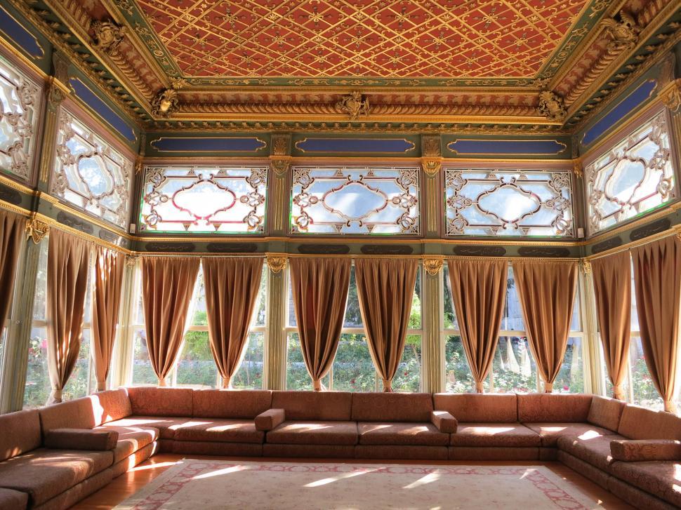 Free Image of Luxurious sunlit room with elaborate golden ceiling decor 