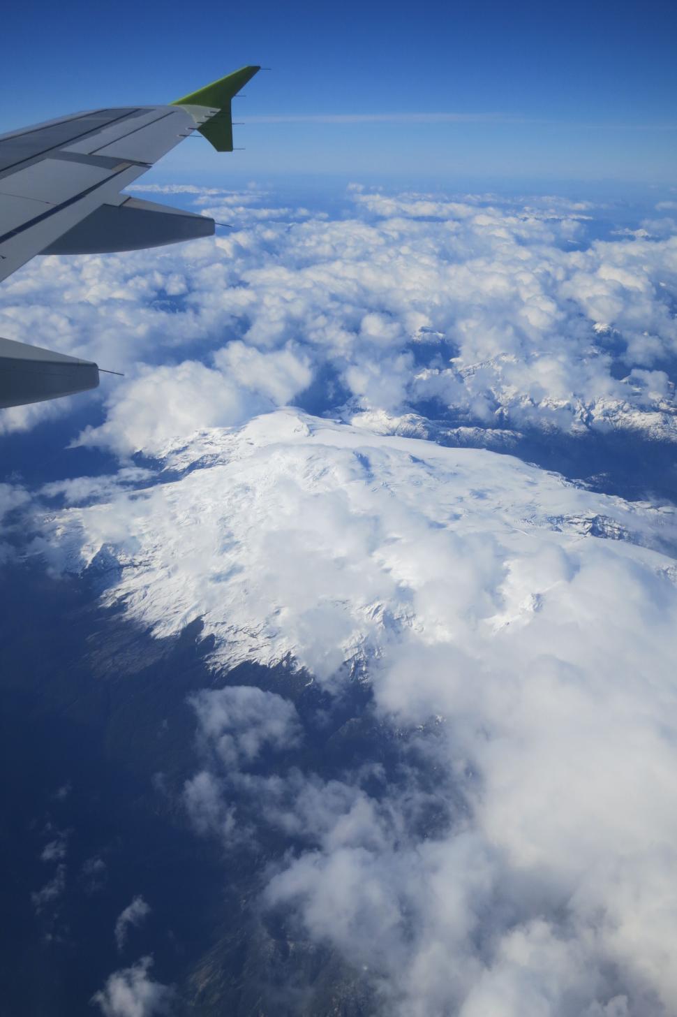 Free Image of Aerial view of snowy mountain capped with clouds. 