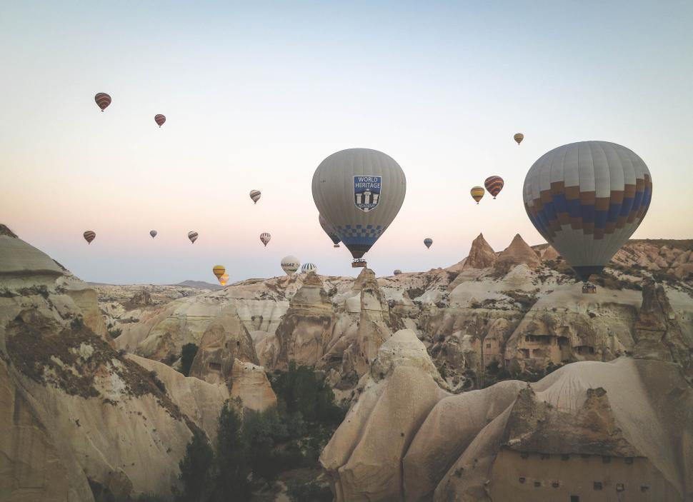 Free Image of Hot air balloons floating over a rocky landscape. 