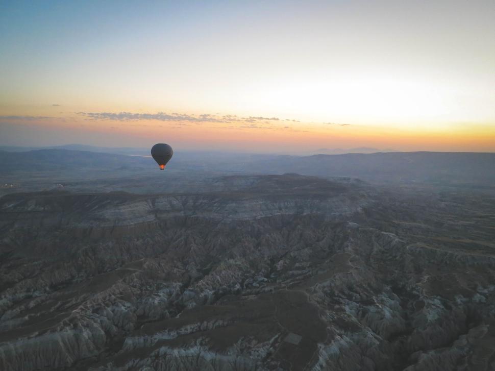 Free Image of Hot air balloon floats over a vast, rugged landscape 
