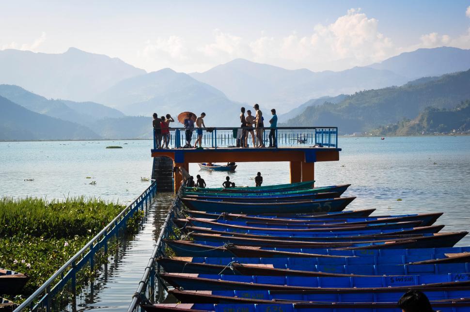Free Image of People on a dock by a lake surrounded by mountains 
