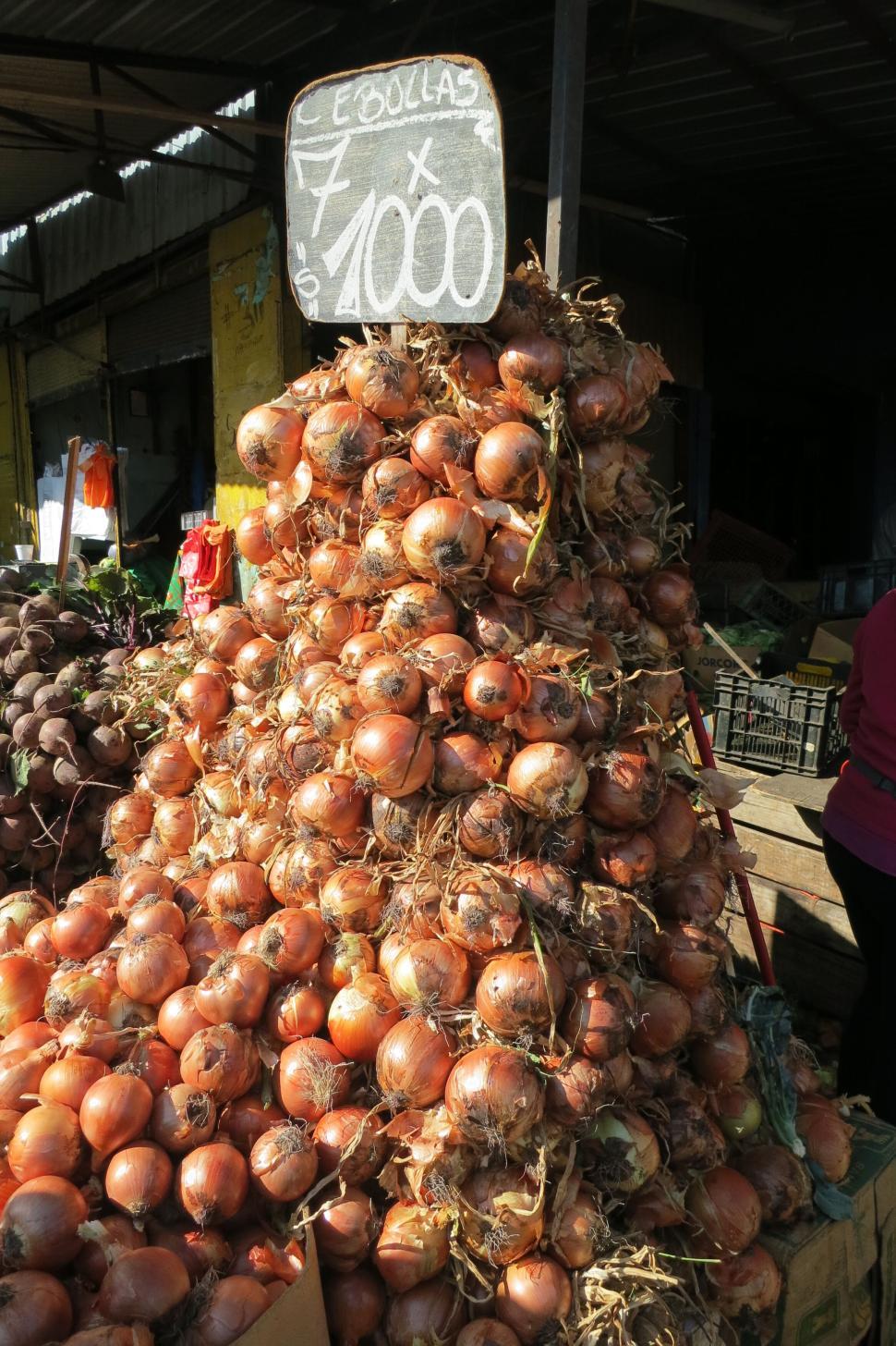 Free Image of High pile of onions for sale at a bustling market 