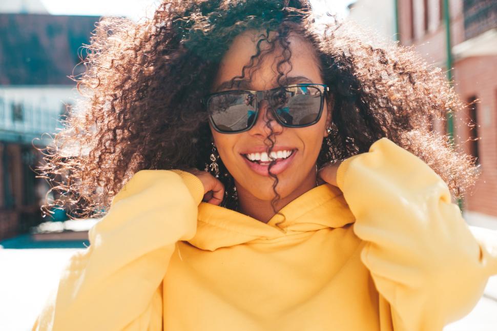 Free Image of Person in yellow hoodie with curly hair, outdoors. 