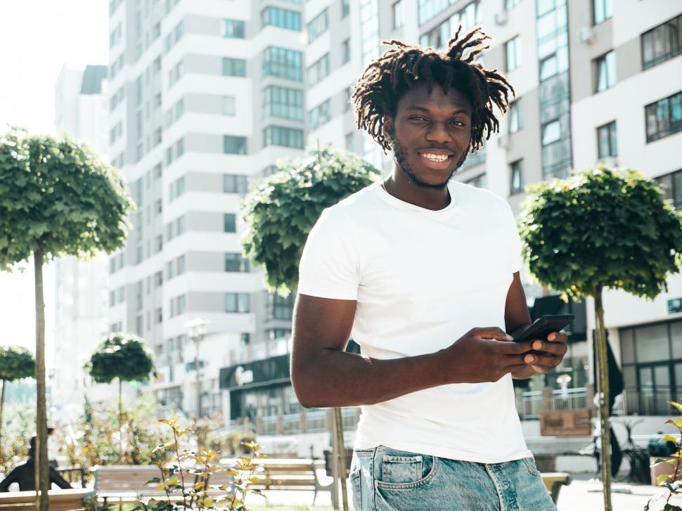 Free Image of Man with dreadlocks and smartphone in urban setting. 